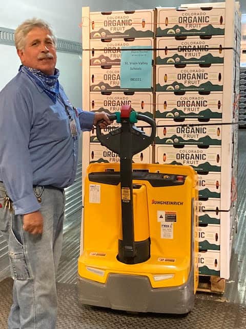 Staff member with pallet full of fresh, Colorado peaches