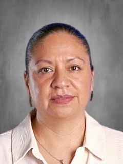 Portrait of a person with a neutral expression, wearing a light-colored shirt, against a gray background.