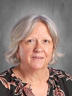 Older woman with short gray hair wearing a floral blouse, set against a neutral background.