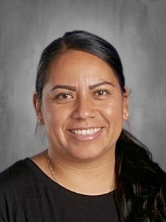 Smiling woman with long dark hair against a gray background.