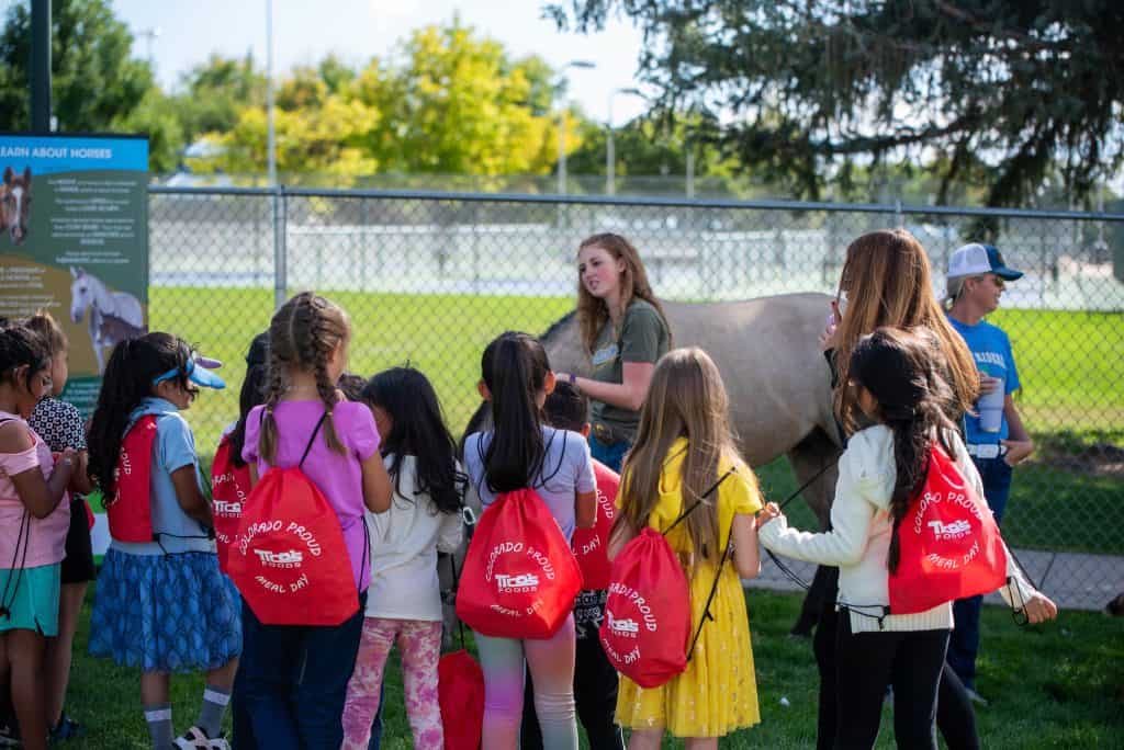 Un grupo de estudiantes observa un caballo durante el Día de las Comidas Escolares Orgullosas de Colorado.