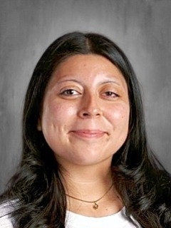 Smiling person with long dark hair against a gray background.