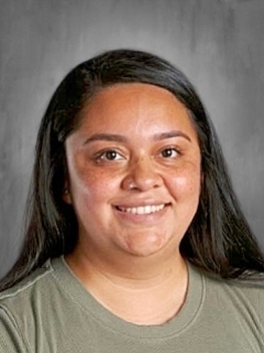 Smiling woman with long dark hair, wearing a green shirt, against a gray background.