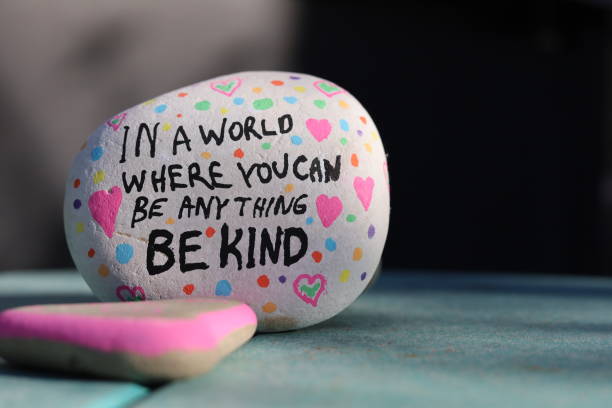 A painted rock with colorful hearts, featuring the message about kindness in a world of choices.